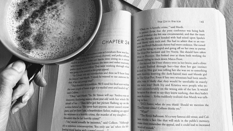 open book on bed with coffee and bookmark